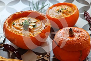 Creamy pumpkin soup and homemade bread on grey tiled table. Soup in a squash top view photo. Thanksgiving menu ideas.Â Â 